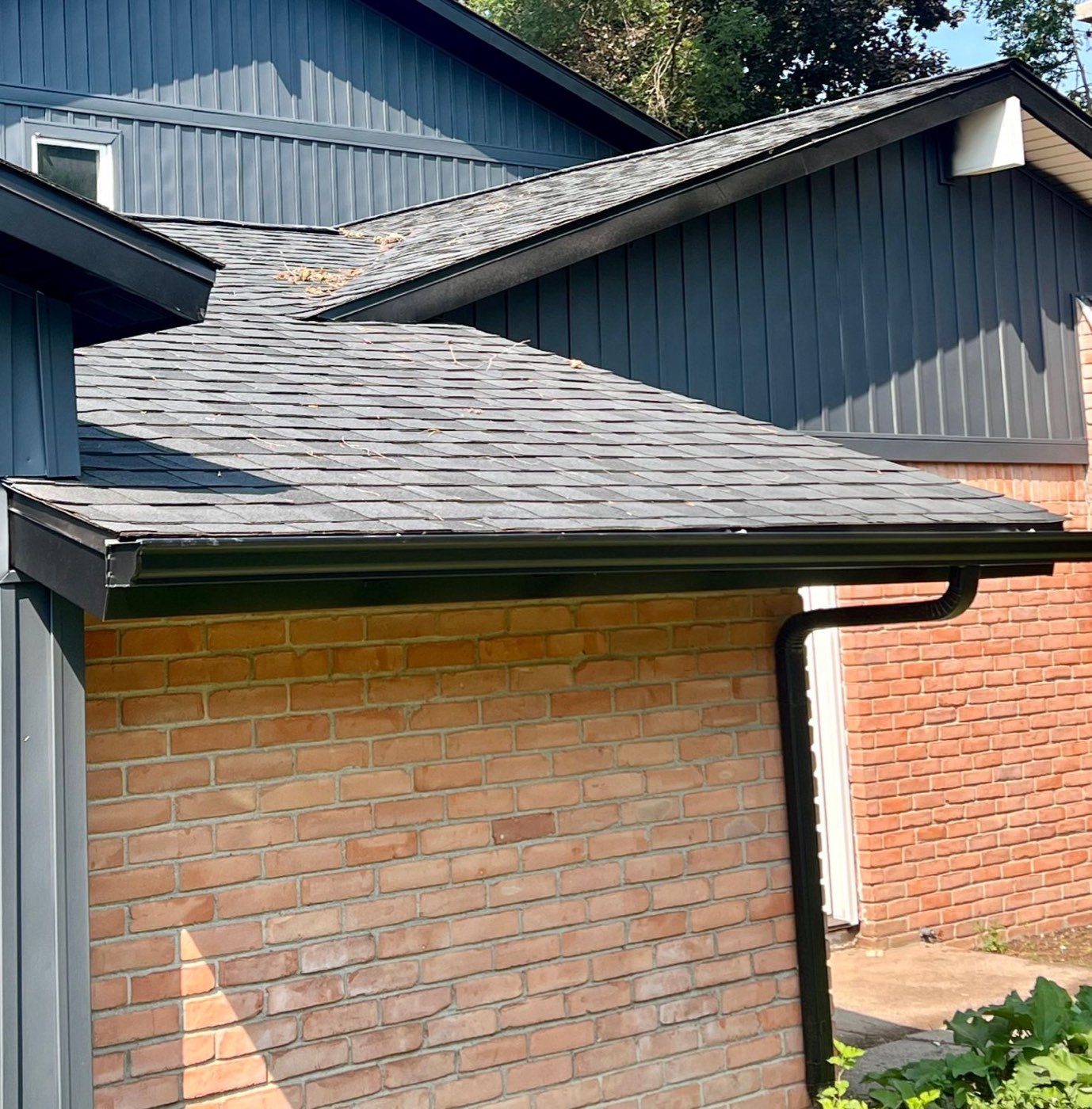 New black gutter and downspout on a home with blue siding